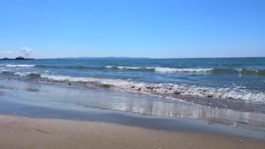 Geniş bir okyanusun geniş açılı görüntüsü. Ritmik dalgalar, parlak gün ışığı altında denizin muazzam güzelliğini yansıtıyor..