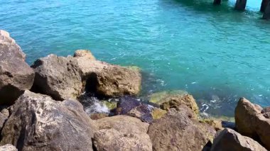 Denize ayrıntılı bir bakış eski bir sahil köprüsünün doğal kayalarına ve kalıntılarına hafifçe çarptı. Güzel doğal tonlar ve yumuşak su hareketi.