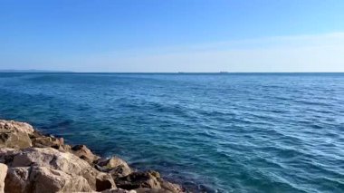 Sakin mavi deniz suyunun geniş açılı görüntüsü ve berrak bir ufuk. Video, denizin dingin güzelliğini yakalıyor, doğa, rahatlama ve kıyı manzarası ile ilgili projeler için mükemmel..