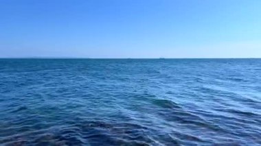 Ufukta uzak bir gemi olan yatay deniz manzarası. Bu sakin sahne açık suları vurguluyor ve seyahat, keşif ve deniz sanayisi temaları için kullanılabilir..