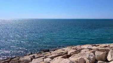 Kıyı boyunca taşlarla dolu güzel bir deniz manzarası huzur verici ve huzur verici bir manzara sunuyor. Bu video doğanın barışçıl güzelliğini yansıtıyor, doğa temalı projeler için ideal..