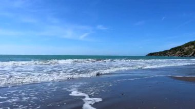 Kumsala vuran dalgalarla huzurlu bir sahil.