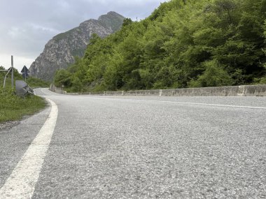Yol sarmaş dolaş bulutlu gökyüzünün altında kayalık kayalıklara sarılıyor. Seyahat, keşif, özgürlük görselleri ve dağlık ulaşım yolları için harika..