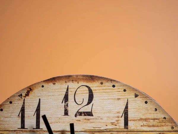 Clock on an orange background. At five minutes to twelve. close-up.