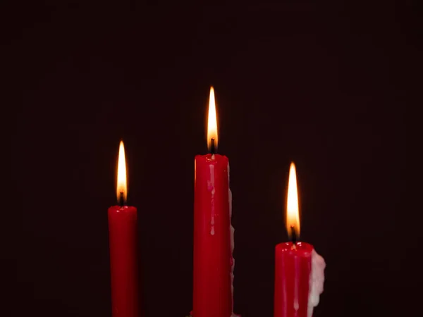 Burning red candles. Burning candles on a dark background. Close-up.