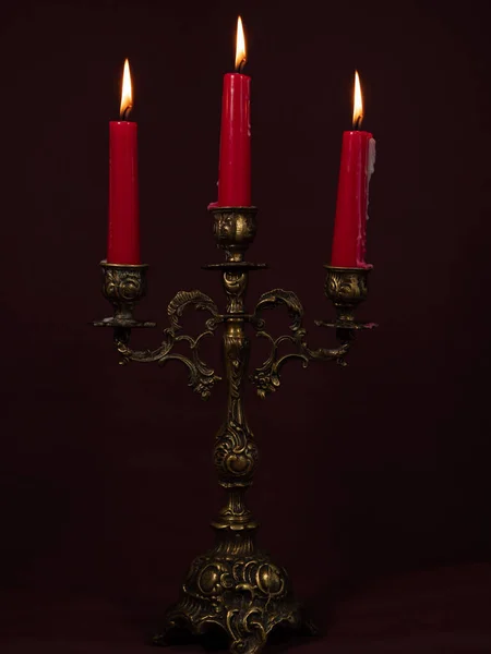 Burning red candles in a candlestick. Lighted candles in an old candlestick. Close-up.