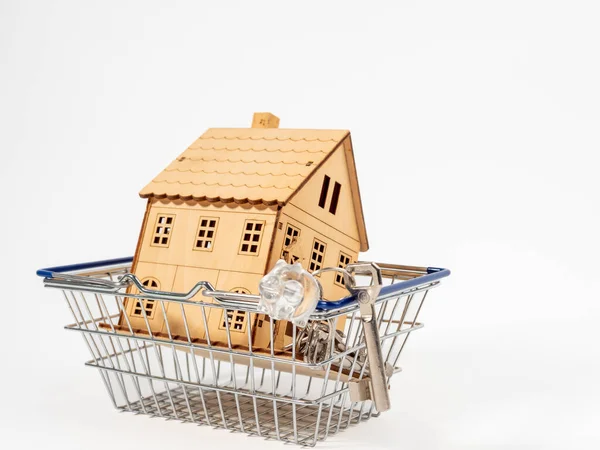 stock image Wooden house in a shopping cart on a white background. The concept of buying a house.