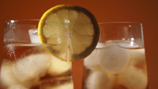 Rotating Iced Tea Glass Ice Cubes Orange Background Cold Tea — Stock Video