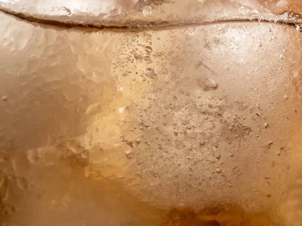Background of ice tea in a glass with ice cubes. Ice tea with ice. Close-up.