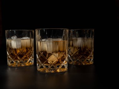 Viski, burbon ya da siyah arka planda buzlu konyak. Yakın plan..