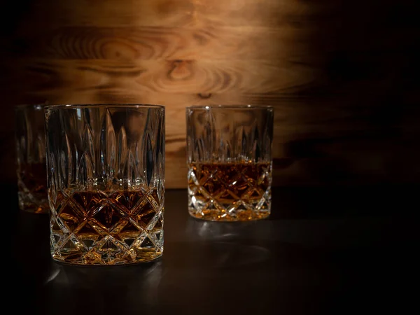Whiskey, bourbon or cognac on a black and wooden background. Close-up.