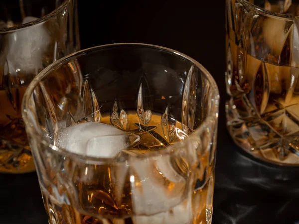 Whiskey, bourbon or cognac with ice cubes on a black background. Close-up.