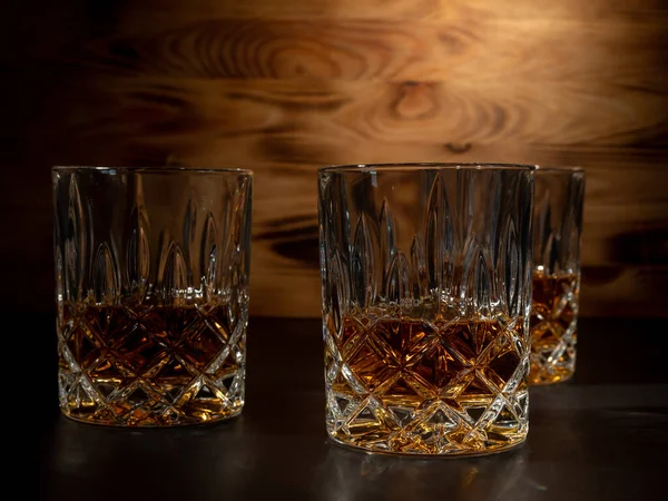 Whiskey, bourbon or cognac on a black and wooden background. Close-up.