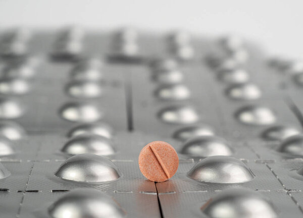 Pink pill on the background of packed pills. medicine in tablets. Close-up.