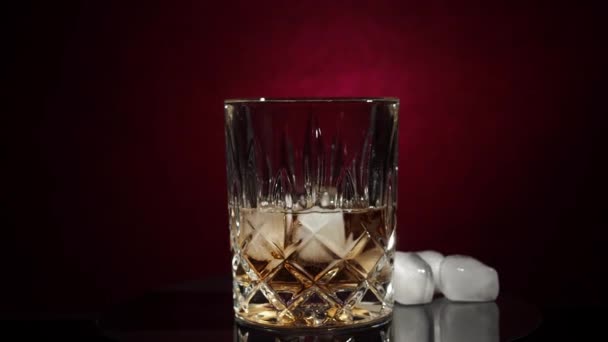 ウイスキー バーボン または黒の背景に氷のキューブとコニャック 高品質4K映像 — ストック動画