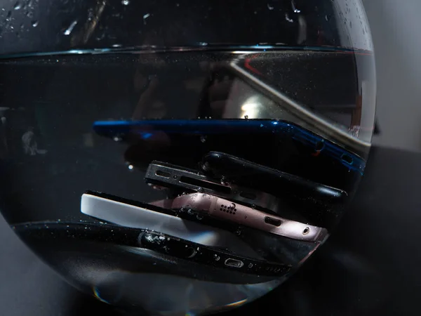 Close-up. Lots of old smartphones in the water on a black background. Wet smartphones.