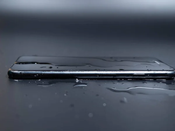 stock image Close-up of an old telephone in water on a black background. Wet smartphone.