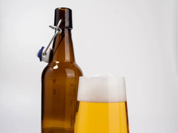 Glass and bottle of beer on a white background. Glass of light beer with foam. close-up.