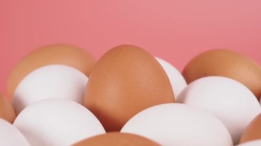 Tavuk yumurtaları pembe arka planda döner. Pembe arka planda yumurtalar.