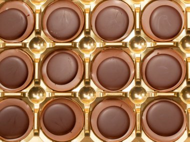 Turuncu arka planda çikolatalı şekerler. Karamelli tatlılar. Yuvarlak çikolatalar. Yakın plan..