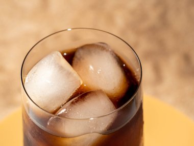 Bardakta buzlu kola. Buzlu karbonatlı içecek. Kola köpükleri. Makro fotoğraf.