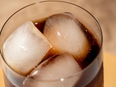 Bardakta buzlu kola. Buzlu karbonatlı içecek. Kola köpükleri. Makro fotoğraf.