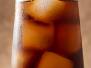 Bardakta buzlu kola. Buzlu karbonatlı içecek. Kola köpükleri. Makro fotoğraf.