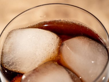 Bardakta buzlu kola. Buzlu karbonatlı içecek. Kola köpükleri. Makro fotoğraf.