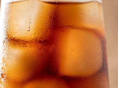 Bardakta buzlu kola. Buzlu karbonatlı içecek. Kola köpükleri. Makro fotoğraf.