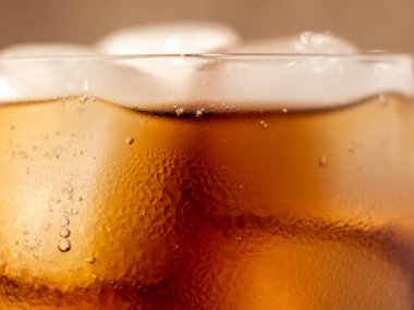 Bardakta buzlu kola. Buzlu karbonatlı içecek. Kola köpükleri. Makro fotoğraf.