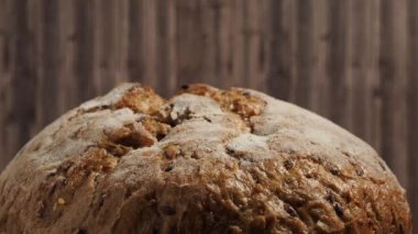 Ahşap arka planda siyah ekmeğin dönüşü. Tahıllı yuvarlak ekmek. Yakın plan..