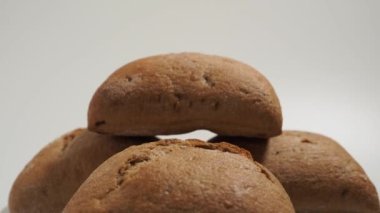 Beyaz arka planda dönen siyah çörekler. Tahıllı fırın ürünleri.