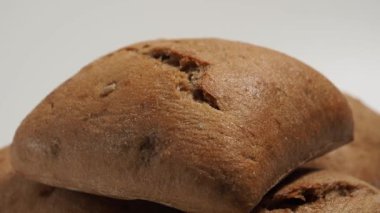 Beyaz arka planda dönen siyah çörekler. Tahıllı fırın ürünleri.