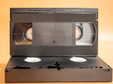 Old VHS cassettes on an orange background. Retro video cassettes. Close-up.