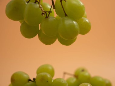 Green grapes. Ripe grapes on an orange background. Close-up.