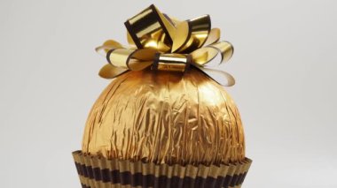 Rotating Chocolate balls wrapped in golden paper. Chocolate bar with golden bow. close-up.