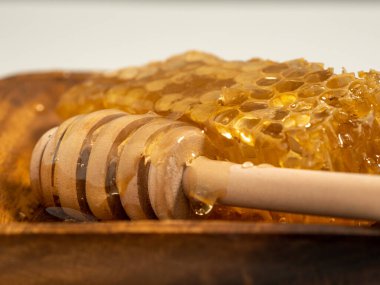 With honeycombs and a wooden spoon for honey in a wooden cup. Honeycombs and honey. Close-up.