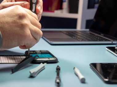 A technician repairs a smartphone in a laboratory with copy space. concept of computer hardware, mobile phones, electronics, repair, upgrade and technology. Close-up.