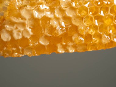 Honey drips from honeycombs. Honeycombs on a gray background. Close-up.