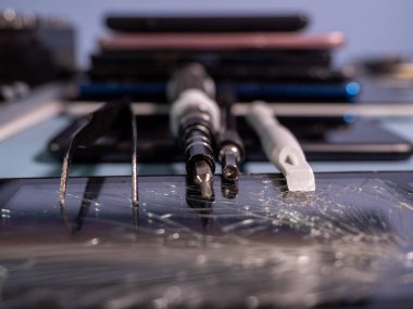 Old broken smartphone and repair tool. The concept of computer equipment, mobile phones, electronics, repair, modernization and technology. Close-up.
