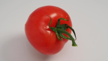 Red tomato rotates on a white background. Red tomato close up.