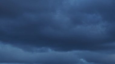 Zaman ayarlı gri bulutlar bulutlu bir günde karanlık gökyüzünde yüzerler. Bulutlu gökyüzü ve kasvetli bulutlar. Büyülü dramatik gökyüzü. Uğursuz bulutlar yavaşça gökyüzünde hareket ediyor..