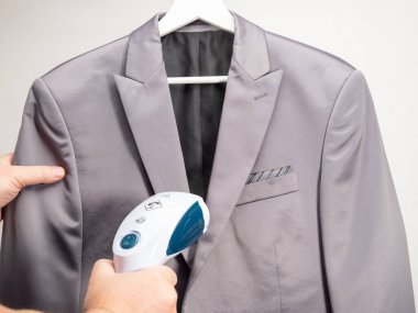 Giysiler için Steamer hazır. Kostüm taşınabilir bir ütüyle ütülendi. Ütü için ütü..