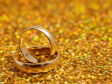 Wedding rings on a golden shiny background. Gold rings. Close-up.
