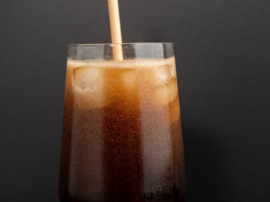 Glass of cola with ice on a black background. Close-up.