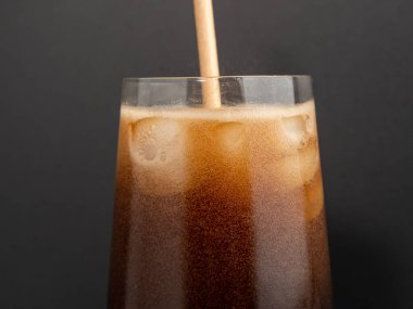 Glass of cola with ice on a black background. Close-up.