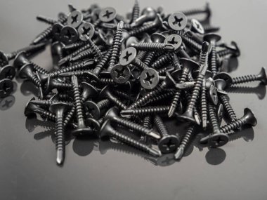 Black screws for drywall on a black background. Close-up.