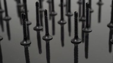 Black Screws. Rotating Black Screws for drywall on a black background. Close-up.