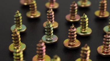 Metal screws on a black background. Rotating screws for driving into plastic. Close-up.