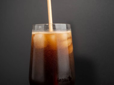 Glass of cola with ice on a black background. Close-up.
